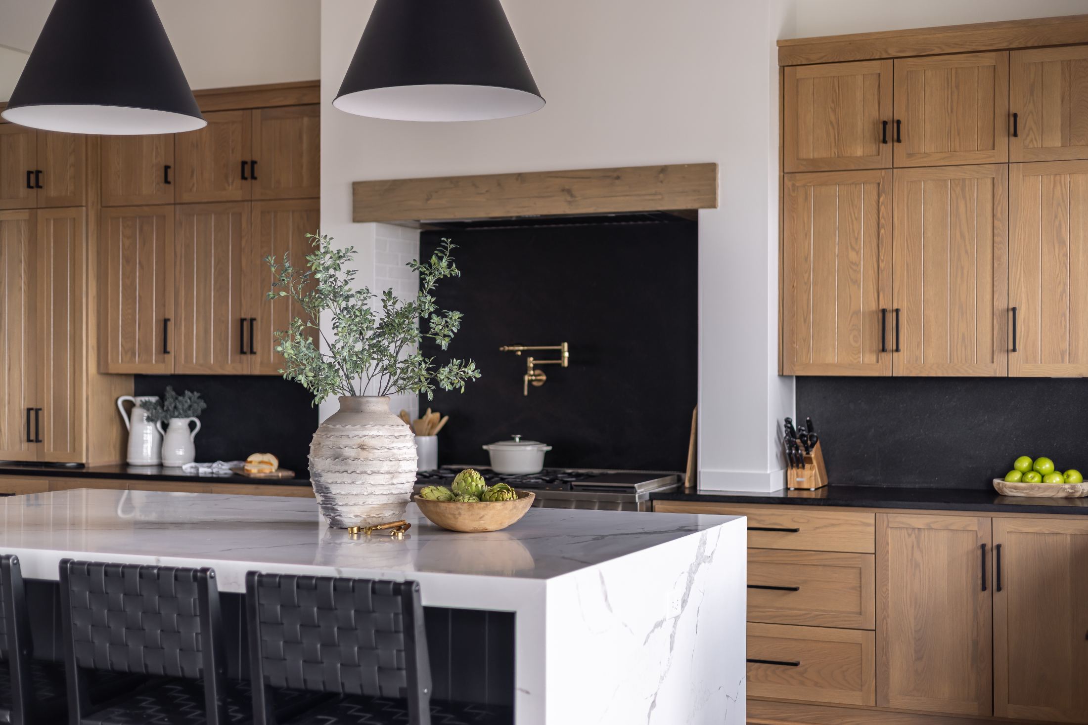 Modern kitchen with wood cabinets, marble island, black backsplash, and pendant lights